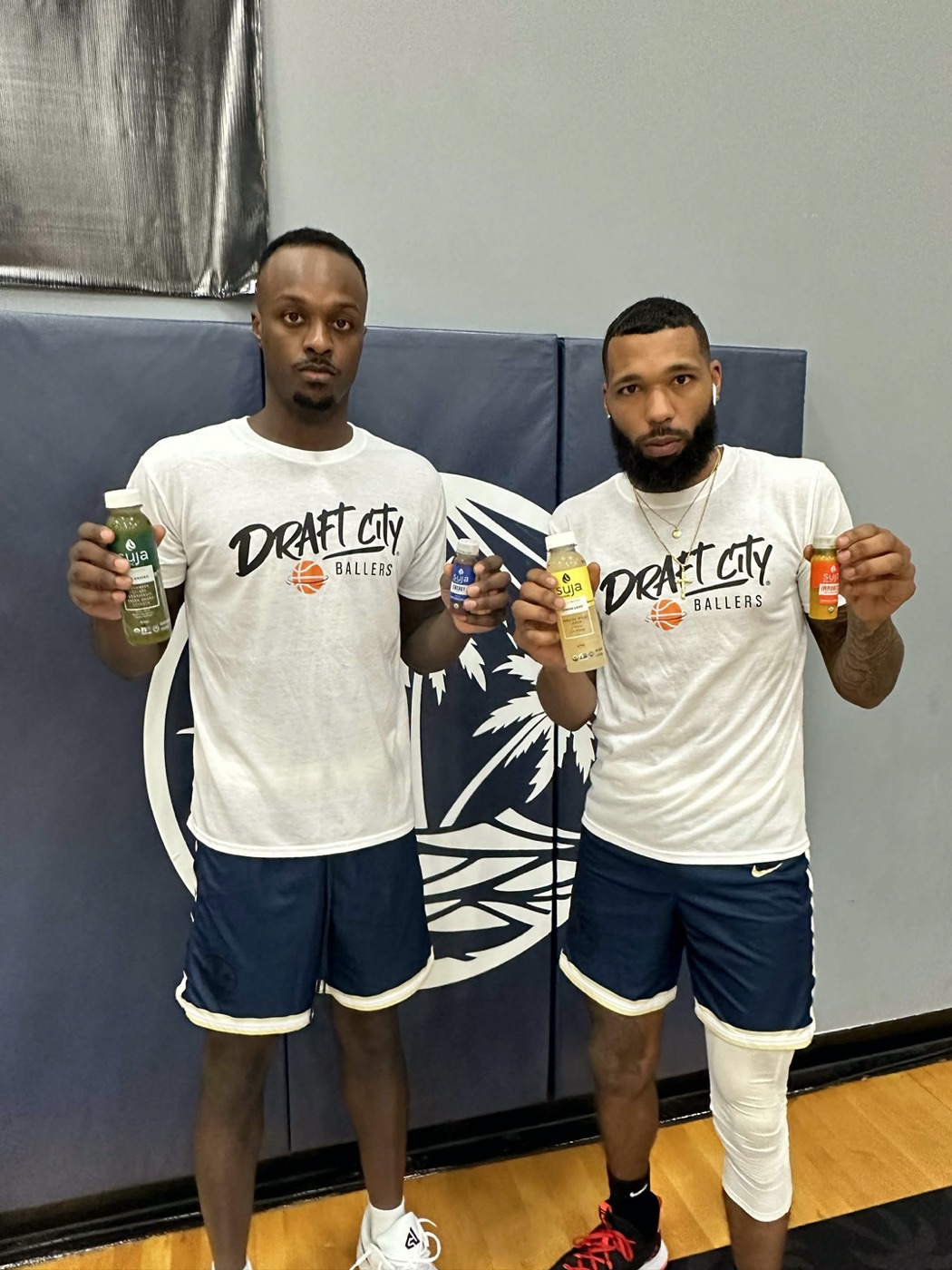 Two Draft City Ballers players holding Suja juices in a gym